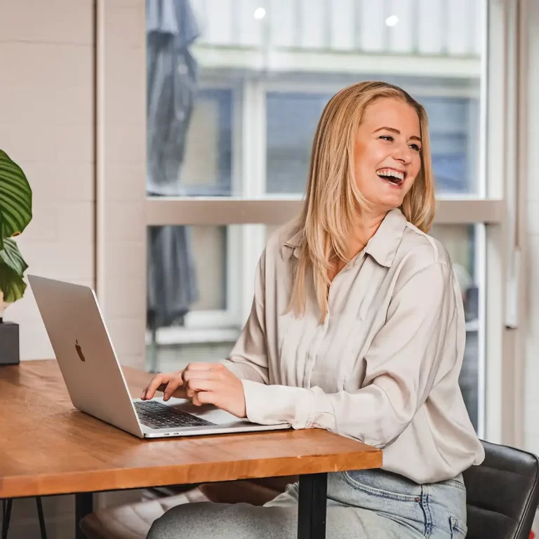 Recruiter lacht achter haar laptop tijdens een online kennismaking